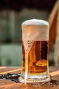 Une pinte de bière mousseuse sur une table en bois.